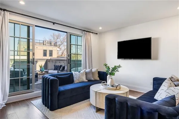 a living room with furniture a flat screen tv and a floor to ceiling window