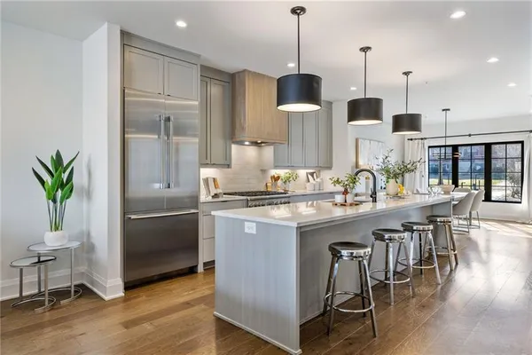 a kitchen with stainless steel appliances a dining table chairs stove and white cabinets