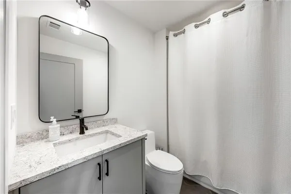 a bathroom with a granite countertop sink toilet and mirror