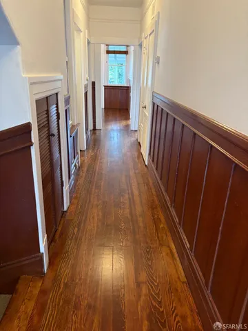 a view of a hallway with wooden floor and staircase