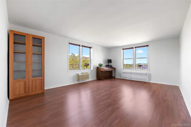 an empty room with wooden floor cabinet and windows