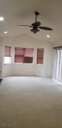 a view of large empty room with a ceiling fan and window