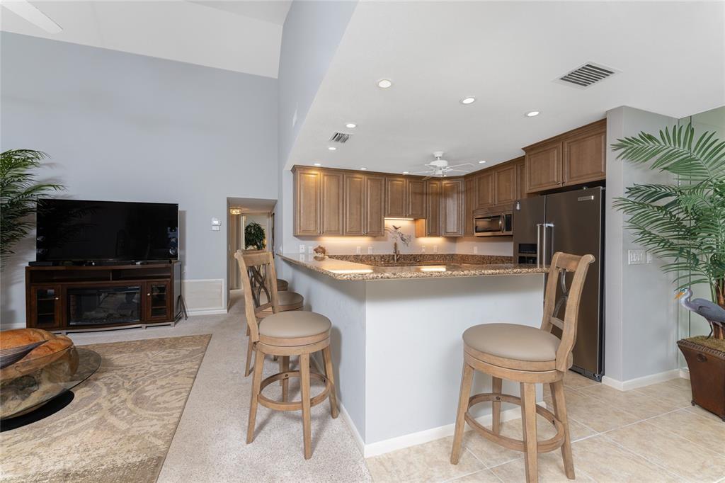 1401 Beach Road, Unit 303 Englewood, FL 34223 - Photo 15 of 63 a kitchen with stainless steel appliances kitchen island granite countertop a sink and a refrigerator