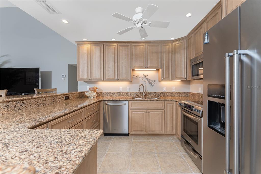 1401 Beach Road, Unit 303 Englewood, FL 34223 - Photo 16 of 63 a kitchen with granite countertop a sink stainless steel appliances and white cabinets