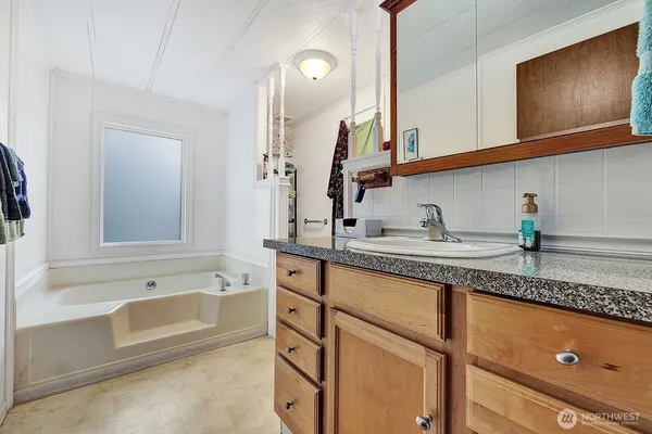a bathroom with a granite countertop sink mirror and bathtub