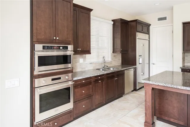 a kitchen with stainless steel appliances granite countertop a sink and a refrigerator