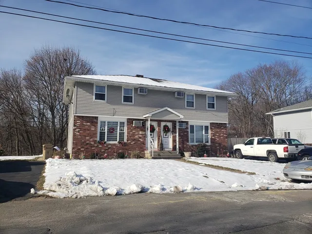 a front view of a house with a yard covered in snow