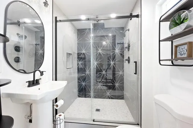 a bathroom with a sink a mirror a glass door a shower and a mirror