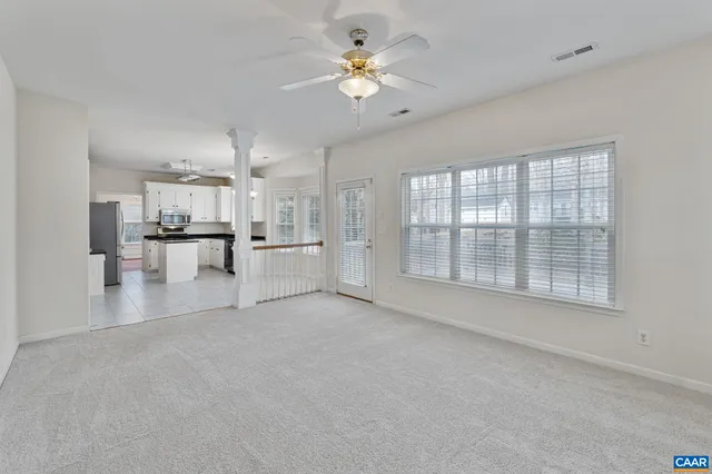 a view of empty room with a kitchen area and a ceiling fan