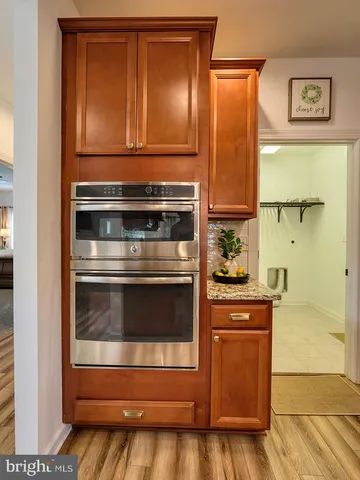 a kitchen with stainless steel appliances granite countertop a refrigerator a sink dishwasher a stove and white countertops with wooden floor