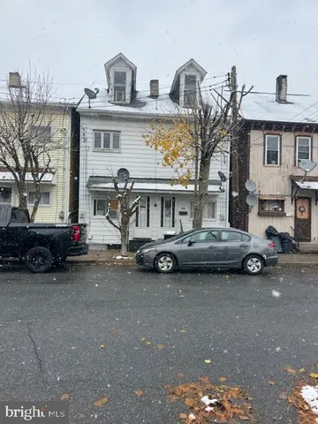 a view of a blue house with a cars parked in front of it