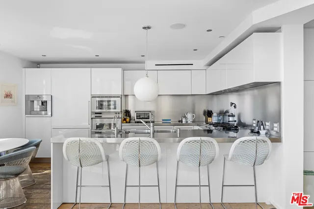 a kitchen with stainless steel appliances kitchen island granite countertop a sink a stove a dining table and chairs