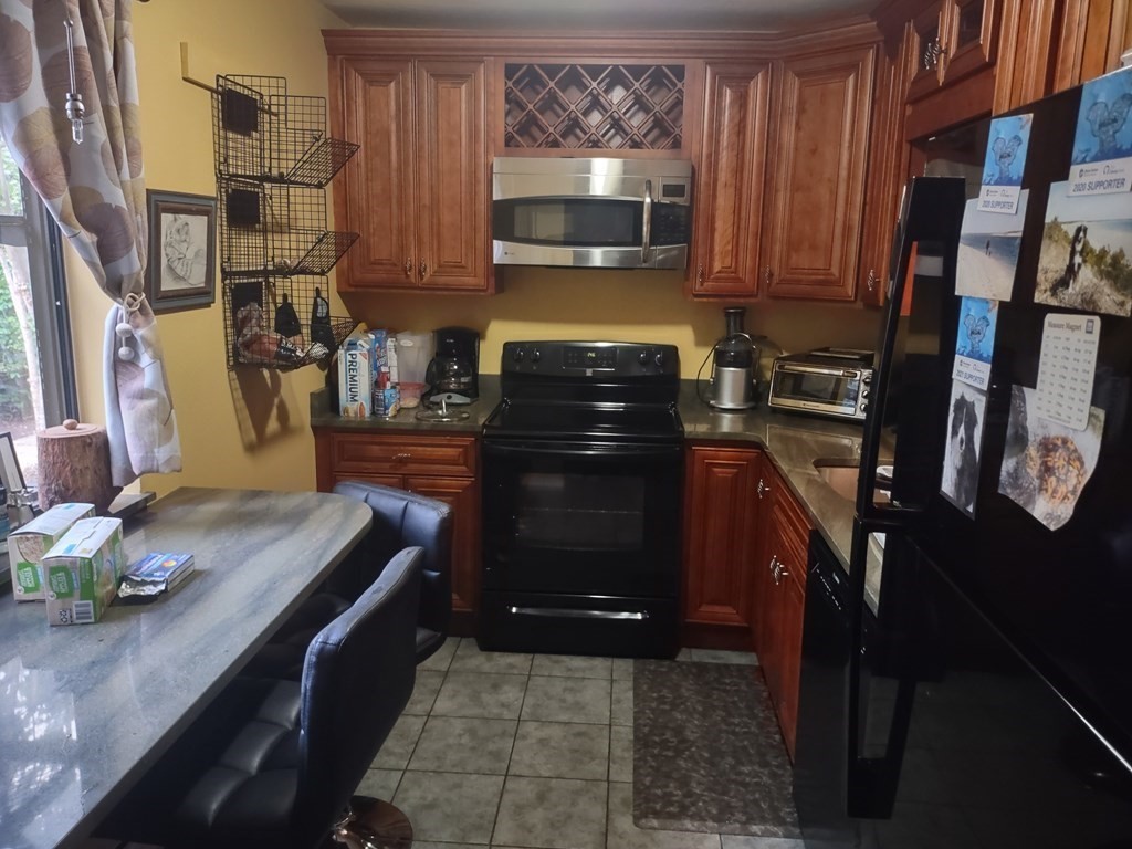 62 Round House Road, Unit 62 Bourne, MA 02532 - Photo 6 of 10 a kitchen with granite countertop a stove top oven microwave and cabinets
