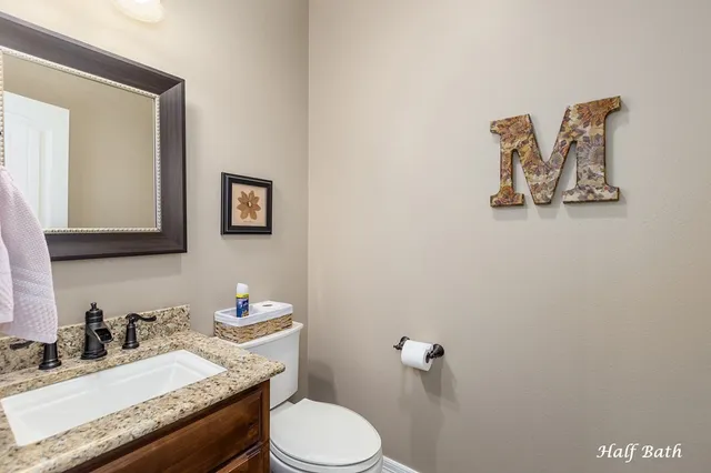 a bathroom with a granite countertop toilet sink and mirror