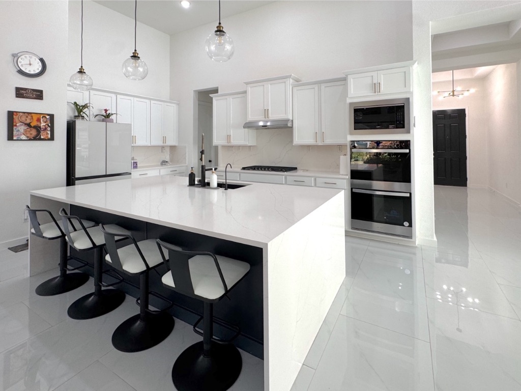 213 Camille Street Leander, TX 78641 - Photo 9 of 27 Kitchen featuring tasteful backsplash, white cabinets, a towering ceiling, a breakfast bar, and double oven