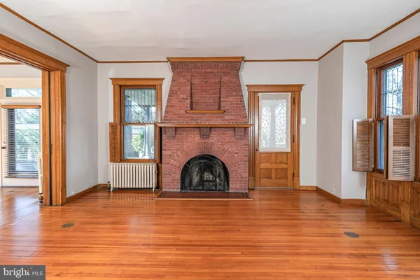 an empty room with wooden floor a fireplace and windows