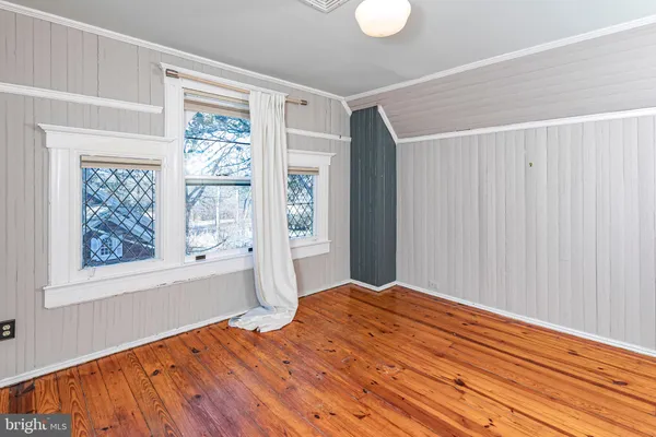 an empty room with wooden floor windows and entryway