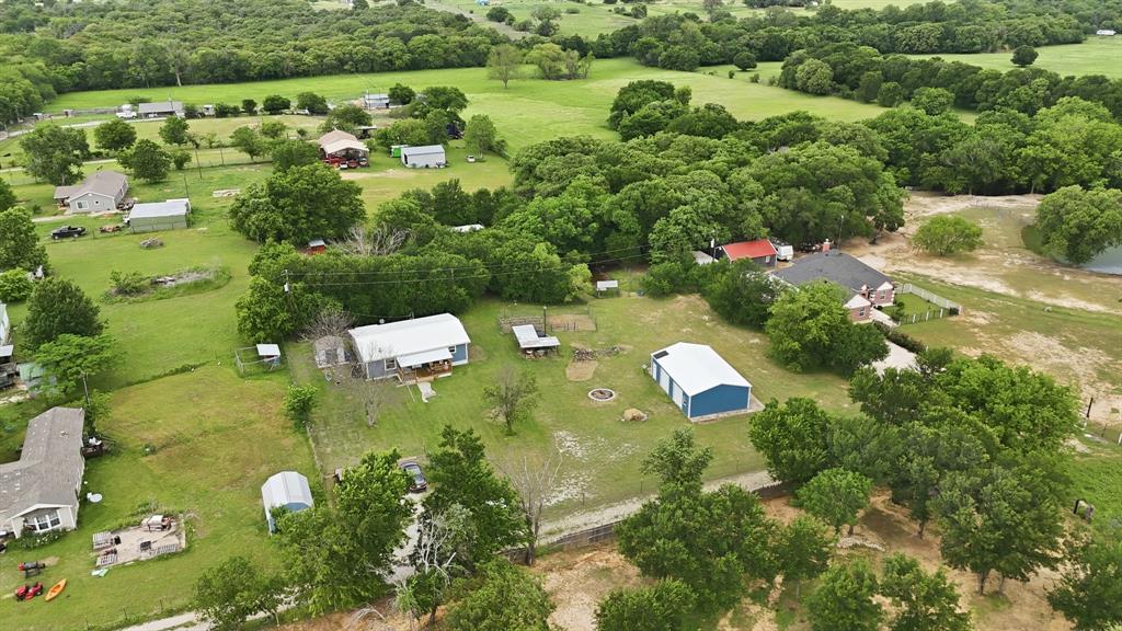 767 East Barry Street Azle, TX 76020 - Photo 11 of 40 This property features several buildings, including a residence with a light-colored roof and a porch, and a blue outbuilding with a white roof