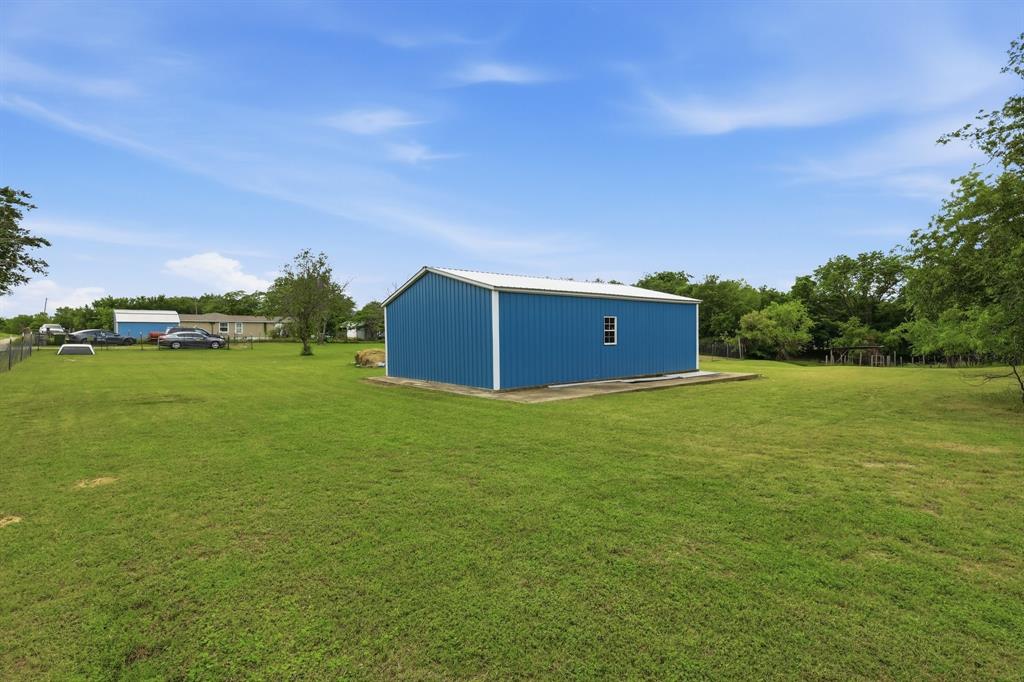 767 East Barry Street Azle, TX 76020 - Photo 13 of 40 The property features a blue metal building with a white roof and a small window, set on a concrete slab