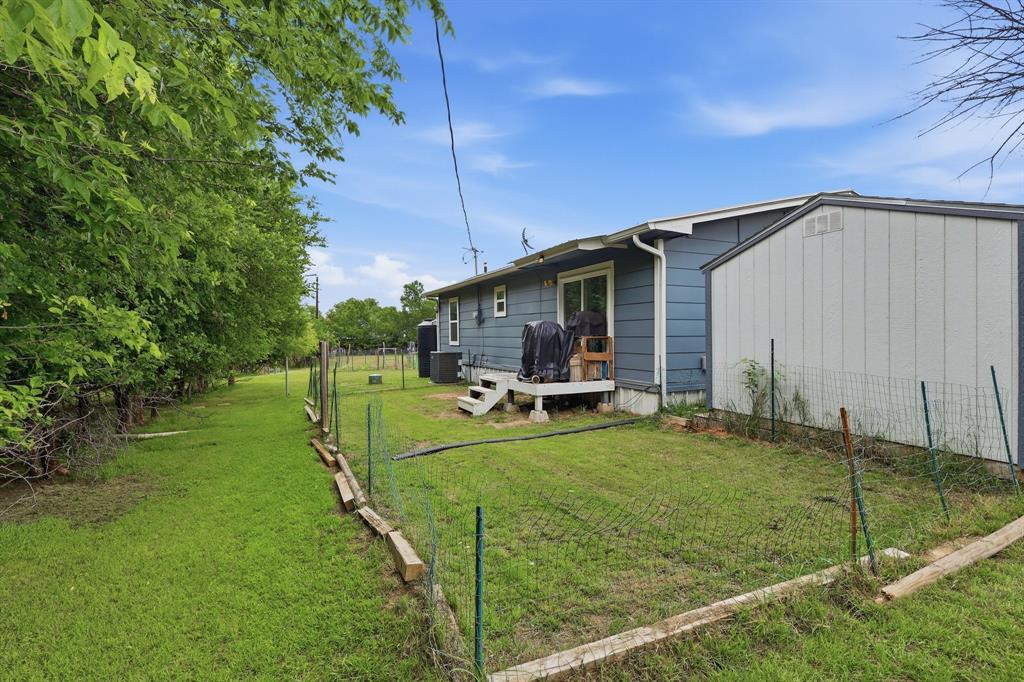 767 East Barry Street Azle, TX 76020 - Photo 20 of 40 The property features a spacious yard with a lush lawn and established trees, offering a private outdoor space