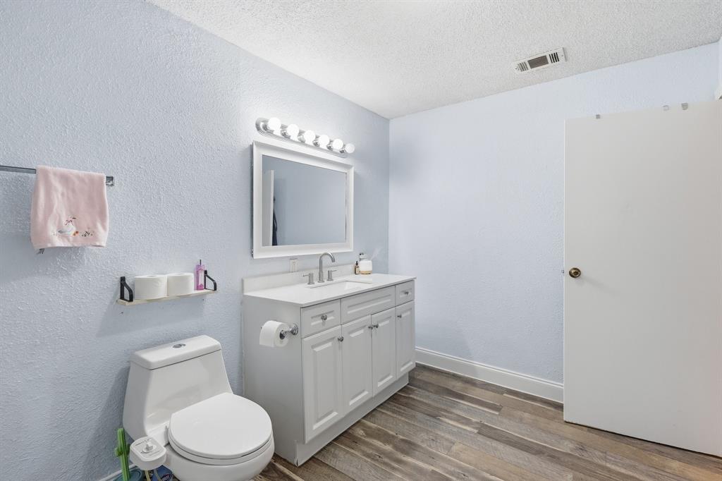 767 East Barry Street Azle, TX 76020 - Photo 28 of 40 Bathroom featuring a white vanity with a single sink, a framed mirror, and a modern light fixture