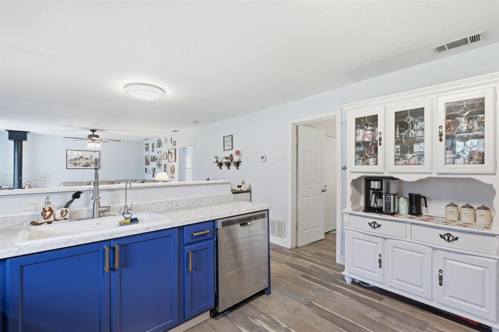 767 East Barry Street Azle, TX 76020 - Photo 32 of 40 The kitchen features blue cabinetry, a white countertop, a white sink with a stainless steel faucet, and a stainless steel dishwasher