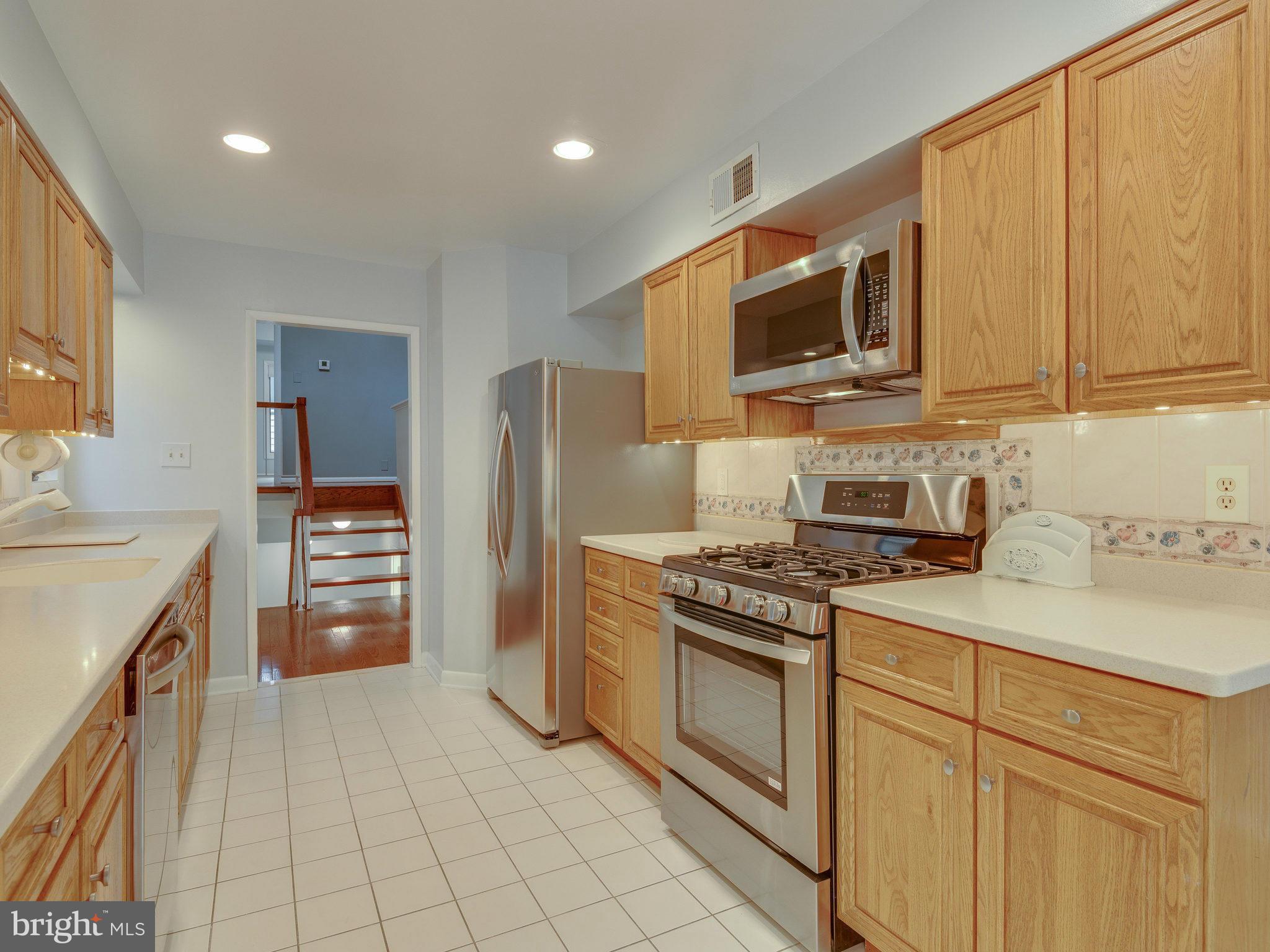 2437 Freetown Drive Reston, VA 20191 - Photo 15 of 30 a kitchen with stainless steel appliances granite countertop a stove top oven a sink dishwasher and a refrigerator with wooden cabinets