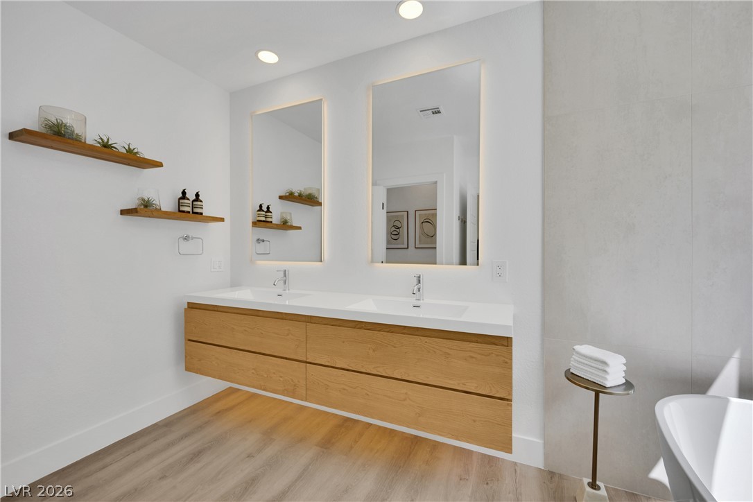 8981 Rivers Edge Drive Las Vegas, NV 89117 - Photo 37 of 69 A spacious primary bathroom boasts a floating double vanity and backlit mirrors for a luminous retreat.