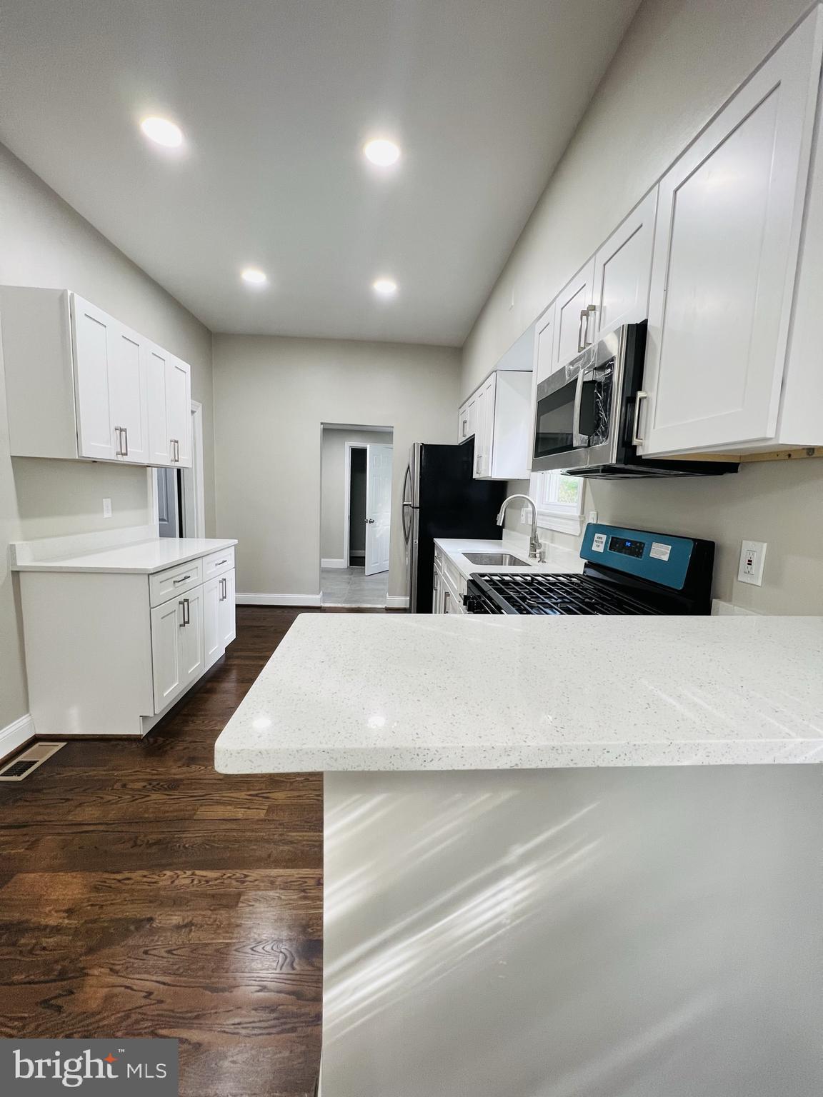 5709 Dade Street Capitol Heights, MD 20743 - Photo 20 of 23 a large white kitchen with kitchen island a sink stainless steel appliances and cabinets