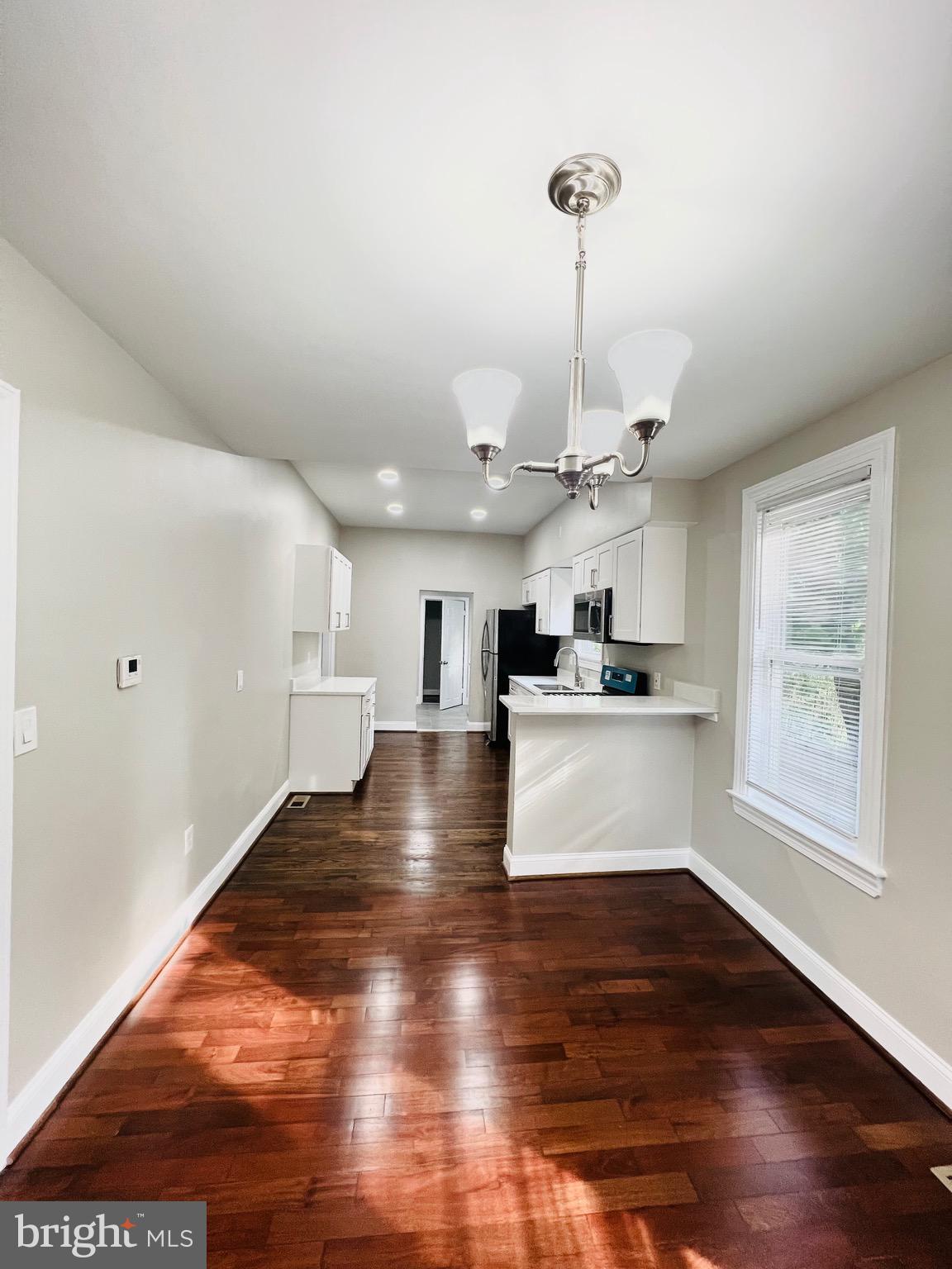 5709 Dade Street Capitol Heights, MD 20743 - Photo 8 of 23 a view of an empty room and kitchen with wooden floor