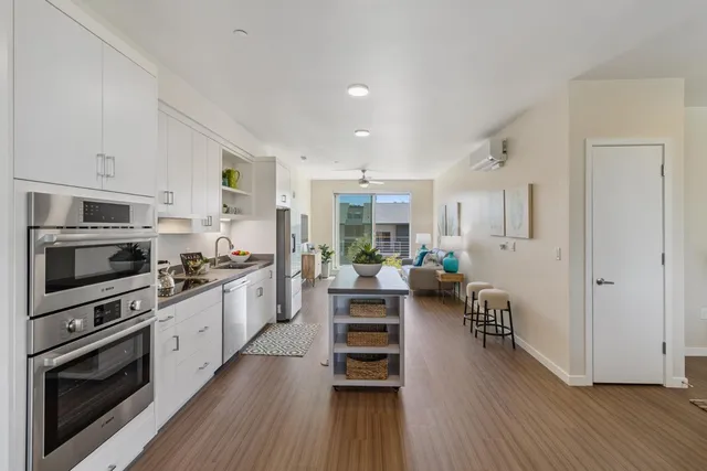 a kitchen with stainless steel appliances a stove a sink a refrigerator cabinets and wooden floor