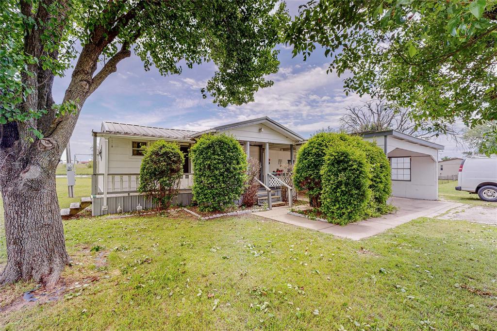 a view of a house with a yard and large tree