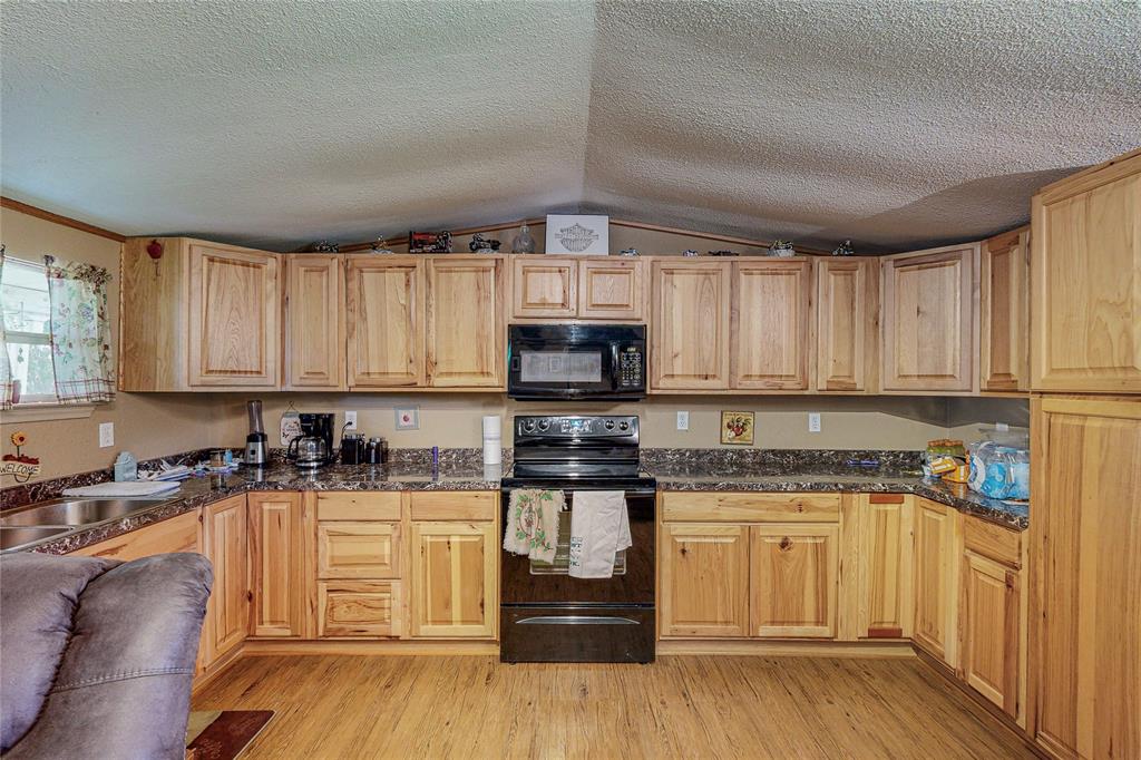1501 Joyce Road Kaufman, TX 75142 - Photo 23 of 37 a kitchen with granite countertop a stove top oven a sink dishwasher and cabinets with wooden floor