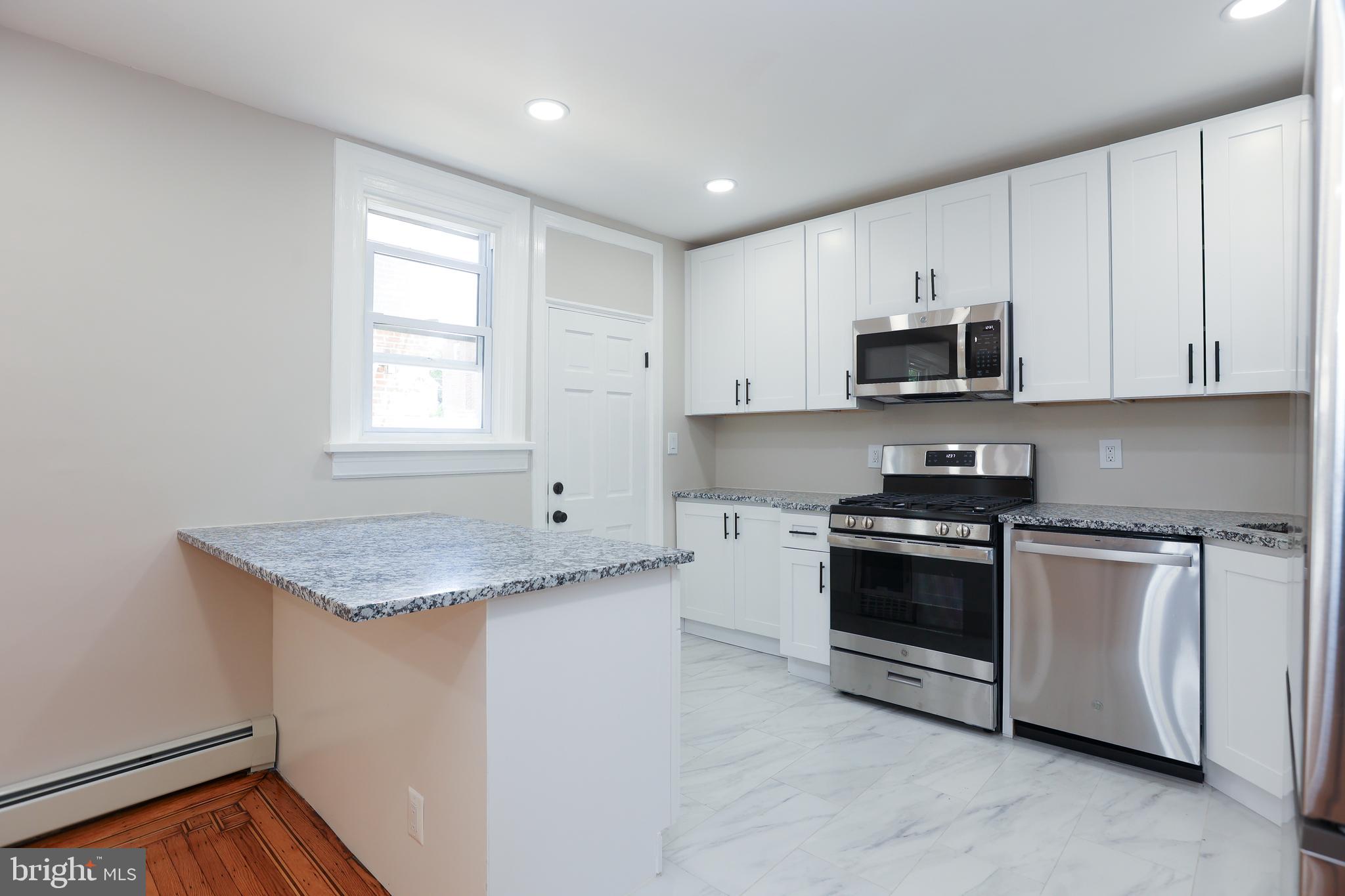 12 East Providence Road Lansdowne, PA 19050 - Photo 7 of 30 a kitchen with stainless steel appliances granite countertop a stove a sink and a microwave