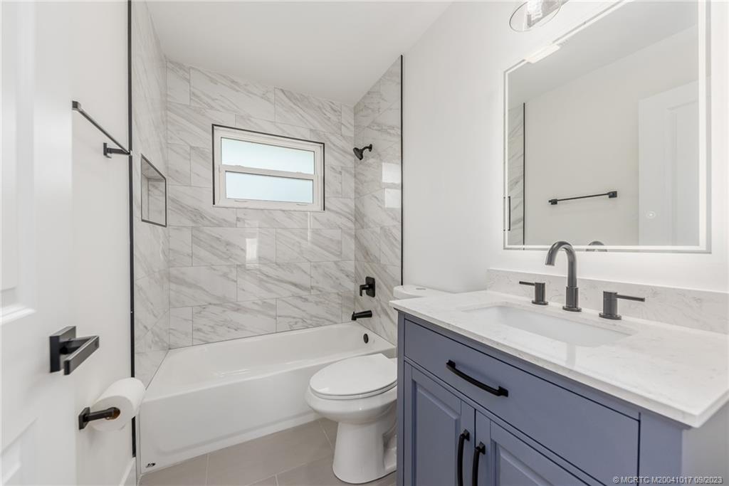 5008 Southeast Major Way Stuart, FL 34997 - Photo 16 of 20 a bathroom with a granite countertop sink a toilet and shower