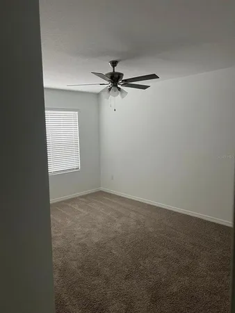 an empty room with windows and fan