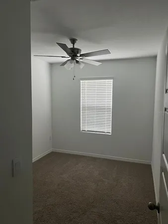 an empty room with a window and a fan