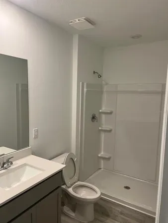 a bathroom with a granite countertop sink toilet and shower