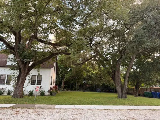 a front view of a house with a garden and trees