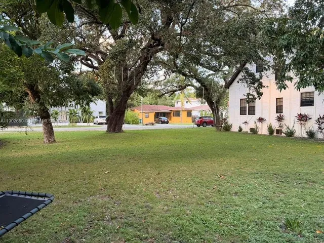 a view of a white house with a big yard and large trees