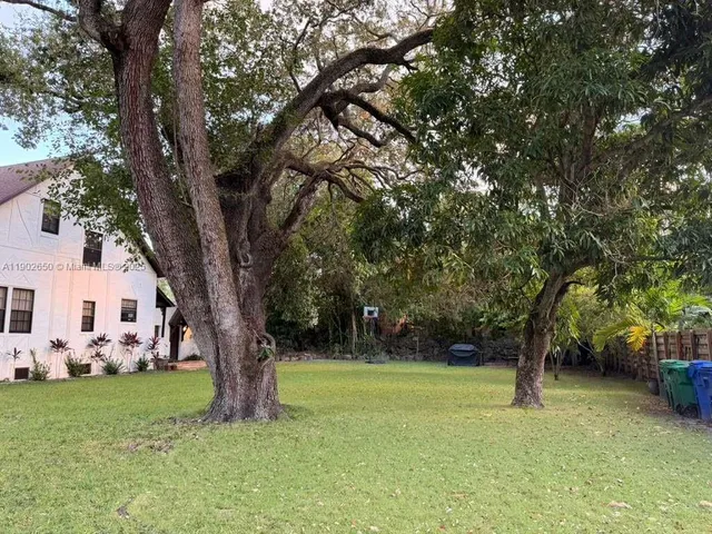 a view of a yard in front of a house with large trees