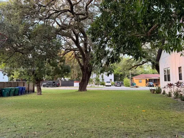 a view of a field with large trees