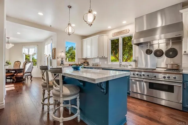 a kitchen with a stove a refrigerator and a dining table with wooden floor