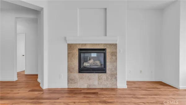 a view of an empty room with wooden floor and a fireplace