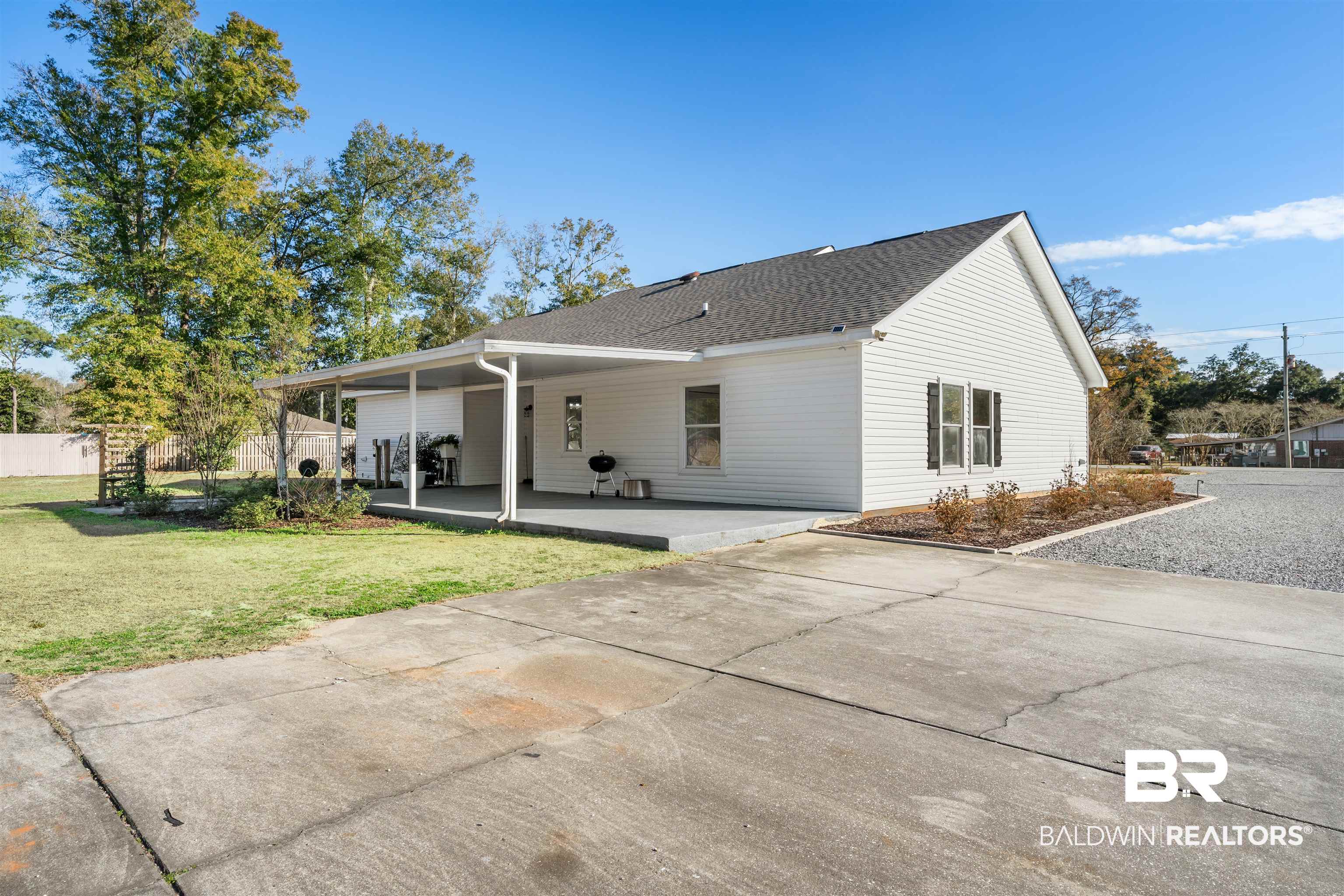 19079 Baldwin County Road 10 Foley, AL 36535 - Photo 32 of 37 Rear view of property featuring a patio, a shingled roof, and concrete driveway
