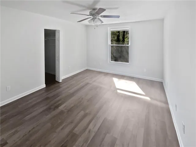 an empty room with wooden floor chandelier fan and windows