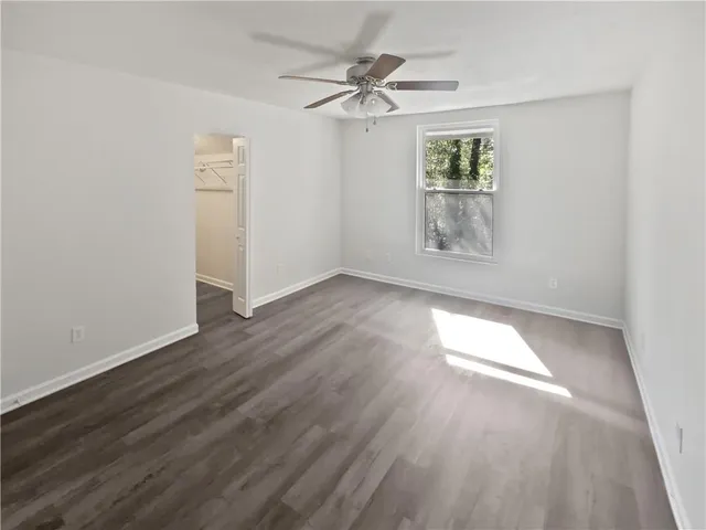 an empty room with wooden floor and ceiling fan