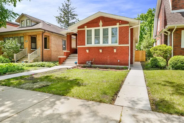 a front view of a house with a yard and potted plants