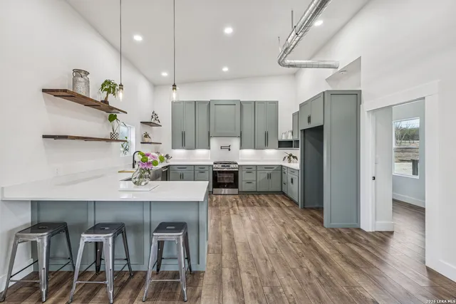 a kitchen with kitchen island a stove a refrigerator and a dining table with wooden floor