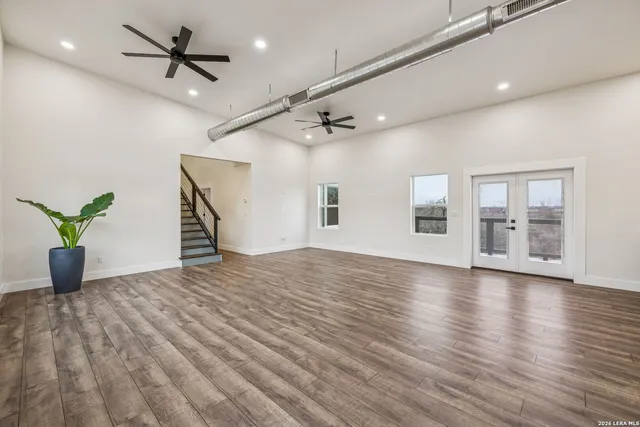 an empty room with wooden floor and a ceiling fan